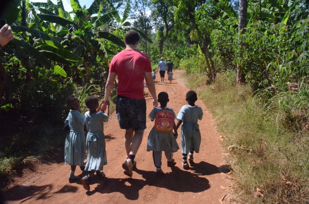 Mirco unterwegs mit Schulkindern in Tansania auf einem Sandweg.