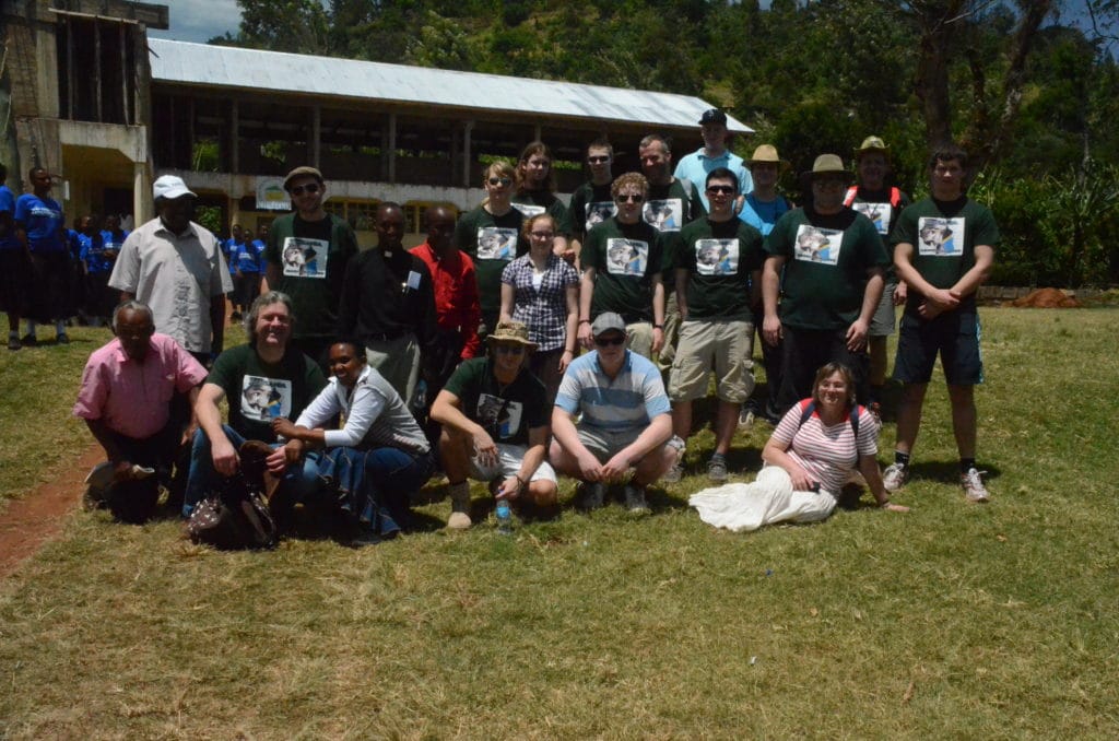 Gruppenfoto eines Ehrenamtlichen-Teams in Tansania vor einer Schule.